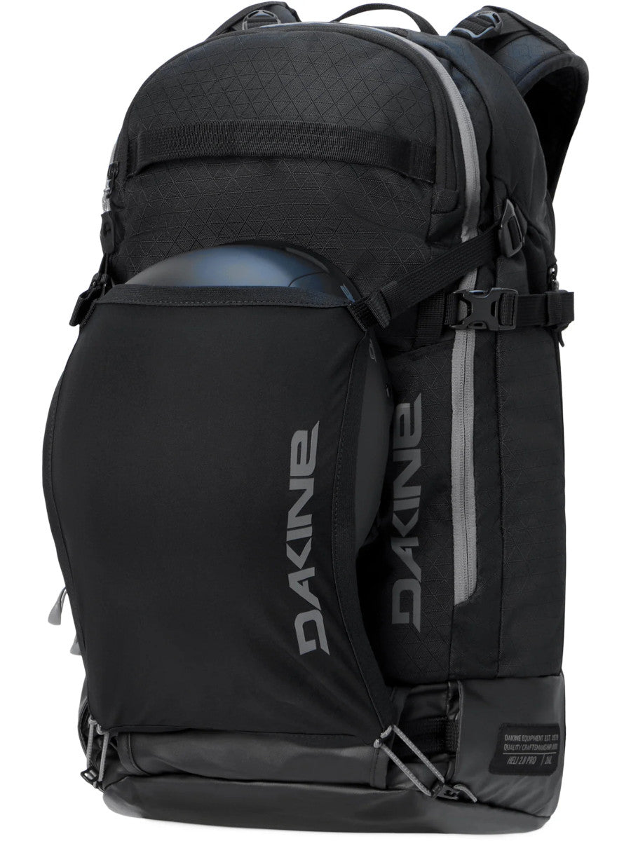 Dakine Heli 2.0 Pro Pack 26L in Black with a helmet held in the stretch front carrier, three-quarter view