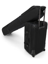 Dakine Fall Line Ski Roller Bag 190cm in Black Coated resting on top of a wheeled suitcase, rear view of the pair travelling together
